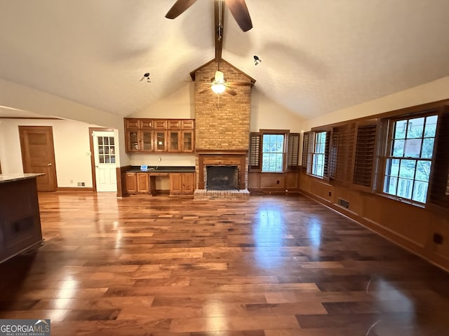 601 Clubland Cir SE, Conyers, GA 30094 - unfurnished living room with a ceiling fan, high vaulted ceiling, beamed ceiling, dark wood-style floors, and a brick fireplace