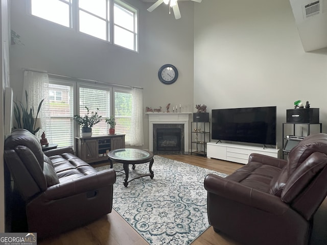2481 Southhaven Ln, Buford, GA 30519 - living room with a high ceiling, plenty of natural light, a glass covered fireplace, wood finished floors, and a ceiling fan