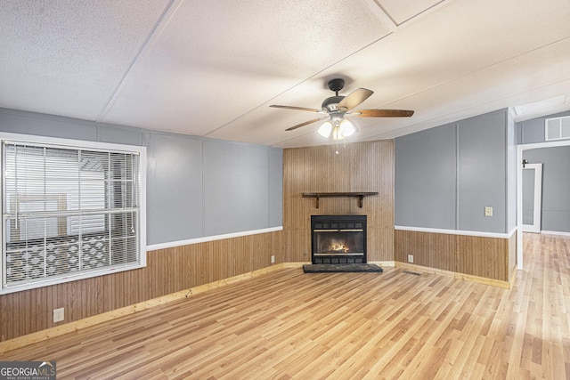 340 Loblolly Rdg, Locust Grove, GA 30248 - unfurnished living room featuring wood finished floors, a fireplace, ceiling fan, wooden walls, and a textured ceiling