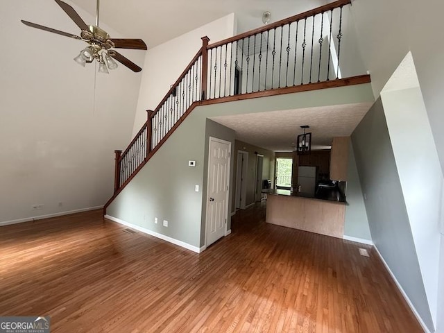 600 Ivory Dr, Baldwin, GA 30511 - unfurnished living room featuring wood finished floors, ceiling fan, a towering ceiling, and stairs
