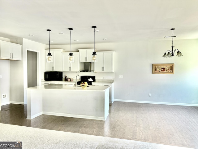 5599 Wheeler Ridge Rd, Auburn, GA 30011 - kitchen featuring wall chimney range hood, wood finished floors, a kitchen island with sink, range, and light countertops