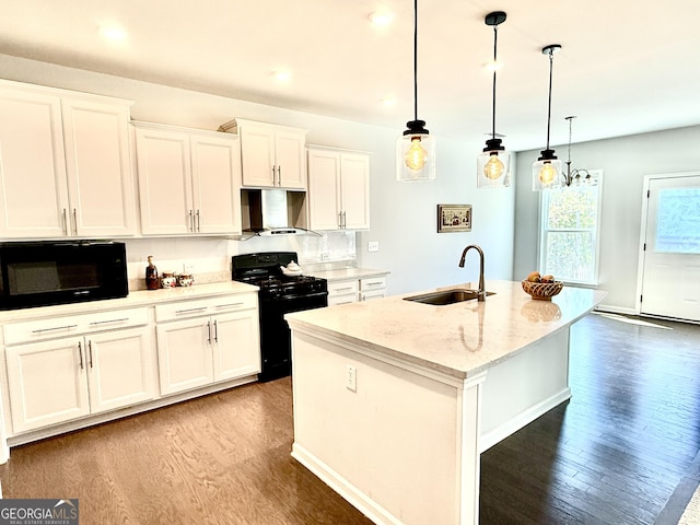 5599 Wheeler Ridge Rd, Auburn, GA 30011 - kitchen featuring black appliances, wall chimney range hood, wood finished floors, a kitchen island with sink, and white cabinetry