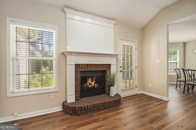 286 Prominent Loop, Mcdonough, GA 30253 - living area featuring wood finished floors, lofted ceiling, a brick fireplace, and healthy amount of natural light