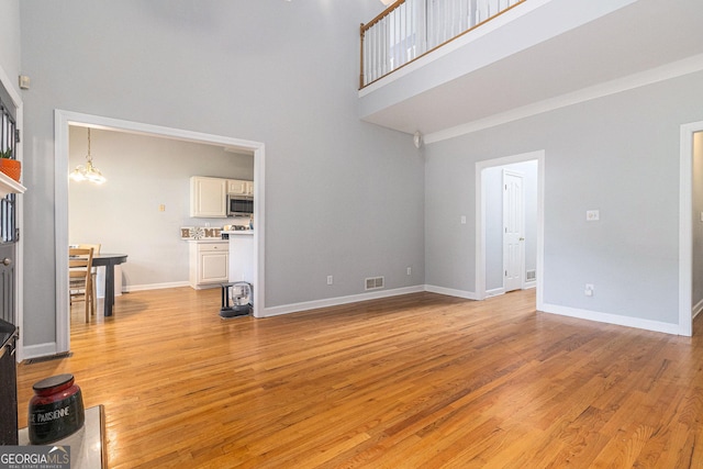 1469 Crescent Walk, Decatur, GA 30033 - unfurnished living room featuring a towering ceiling, light wood-style floors, and a chandelier