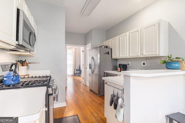 1469 Crescent Walk, Decatur, GA 30033 - kitchen with stainless steel appliances, white cabinetry, light wood finished floors, light countertops, and a peninsula