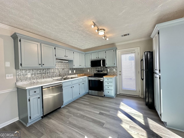 4035 Winchester Way, Loganville, GA 30052 - kitchen with appliances with stainless steel finishes, light countertops, backsplash, crown molding, and light wood-type flooring