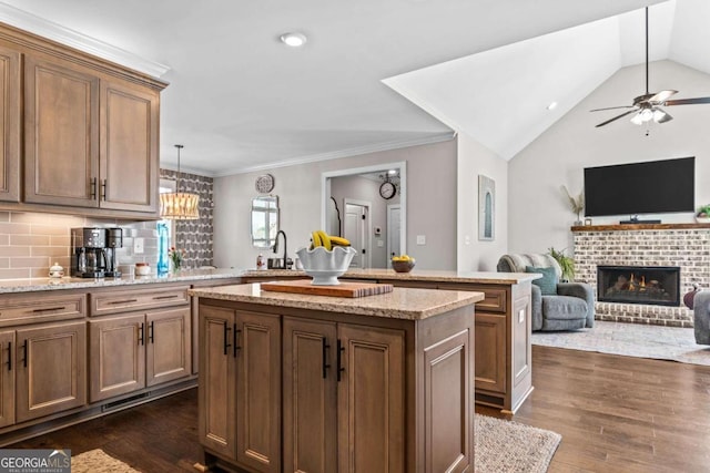 1118 Coralbell Dr, Statham, GA 30666 - kitchen featuring a center island, a brick fireplace, open floor plan, dark wood-type flooring, and ceiling fan