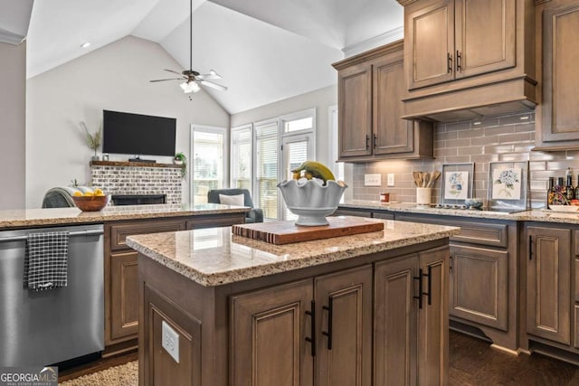 1118 Coralbell Dr, Statham, GA 30666 - kitchen featuring stainless steel dishwasher, ceiling fan, vaulted ceiling, a fireplace, and decorative backsplash