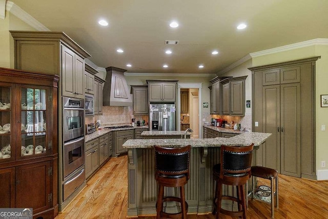 2052 Trimleston Rd, Statham, GA 30666 - kitchen featuring appliances with stainless steel finishes, custom range hood, recessed lighting, light wood-style floors, and a breakfast bar area