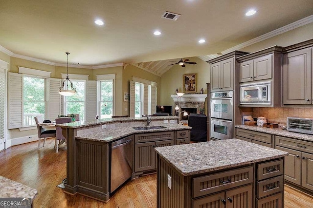 2052 Trimleston Rd, Statham, GA 30666 - kitchen with stainless steel appliances, an island with sink, a ceiling fan, a fireplace, and light wood-style floors
