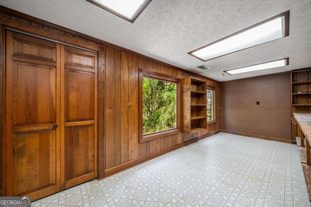 1690 Trotters Ln, Stone Mountain, GA 30087 - unfurnished room featuring a textured ceiling, wooden walls, ornamental molding, and light floors