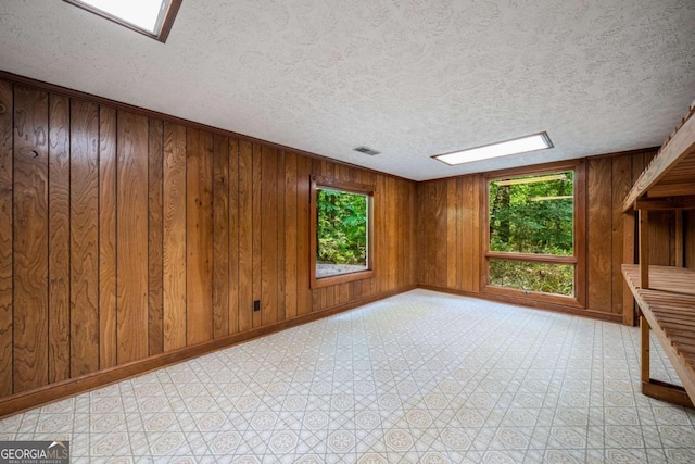 1690 Trotters Ln, Stone Mountain, GA 30087 - unfurnished room with light flooring, a textured ceiling, wood walls, and a skylight