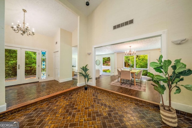 1690 Trotters Ln, Stone Mountain, GA 30087 - foyer entrance with a chandelier, high vaulted ceiling, brick patterned floors, and french doors