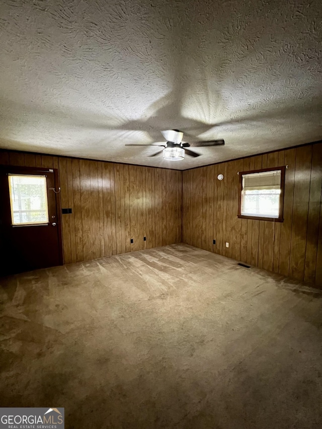 415 Willa Ln, Dublin, GA 31021 - empty room featuring light colored carpet, plenty of natural light, ceiling fan, a textured ceiling, and wooden walls
