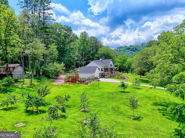 533 Ledford Rd, Dillard, GA 30537 - view of green lawn featuring concrete driveway, an outdoor structure, a wooded view, and an attached garage