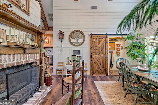 533 Ledford Rd, Dillard, GA 30537 - dining space featuring a barn door, wood walls, a brick fireplace, and dark wood finished floors