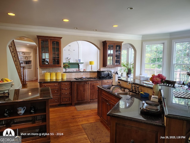 1292 Hidden Spirit Trl, Lawrenceville, GA 30045 - kitchen with arched walkways, black microwave, an island with sink, glass insert cabinets, and ornamental molding