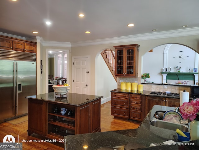 1292 Hidden Spirit Trl, Lawrenceville, GA 30045 - kitchen with appliances with stainless steel finishes, arched walkways, light wood-style floors, ornamental molding, and glass insert cabinets