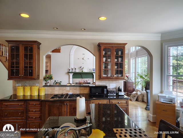 1292 Hidden Spirit Trl, Lawrenceville, GA 30045 - kitchen with black microwave, gas stovetop, decorative backsplash, glass insert cabinets, and arched walkways