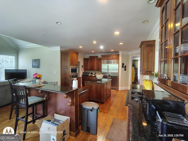 1292 Hidden Spirit Trl, Lawrenceville, GA 30045 - kitchen with built in appliances, a kitchen island, crown molding, a kitchen bar, and light wood-style floors