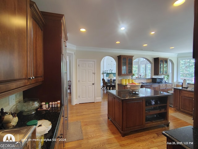 1292 Hidden Spirit Trl, Lawrenceville, GA 30045 - kitchen with arched walkways, ornamental molding, glass insert cabinets, light wood-style flooring, and recessed lighting