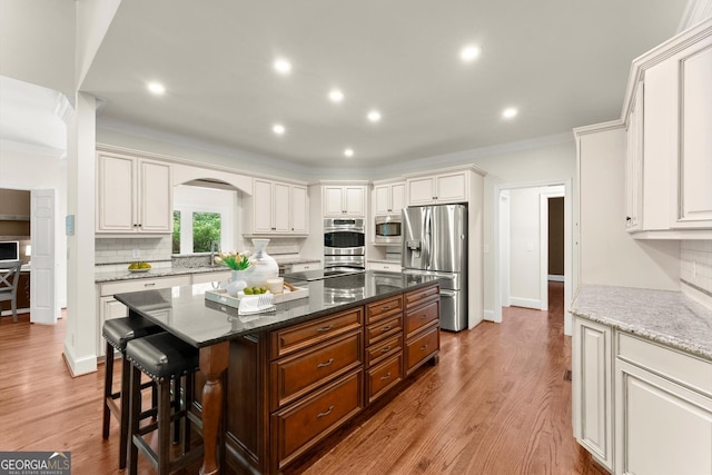 5455 Malone Ct, Powder Springs, GA 30127 - kitchen with stainless steel appliances, crown molding, arched walkways, a kitchen island, and a kitchen bar