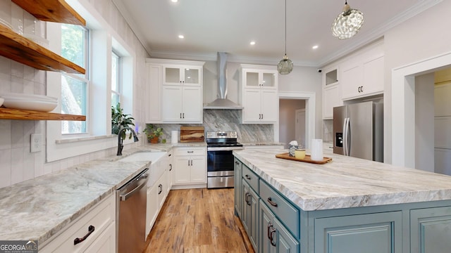 1437 18th St, Columbus, GA 31901 - kitchen with appliances with stainless steel finishes, wall chimney range hood, plenty of natural light, white cabinetry, and ornamental molding