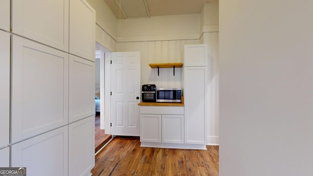 1437 18th St, Columbus, GA 31901 - kitchen with stainless steel microwave, open shelves, wood finished floors, and white cabinetry