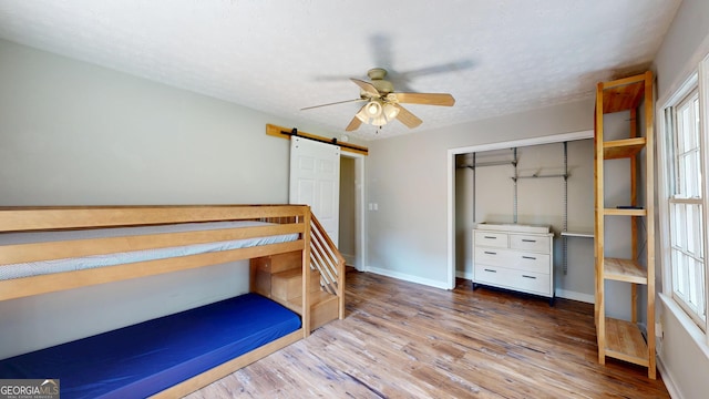 1437 18th St, Columbus, GA 31901 - unfurnished bedroom featuring a barn door, wood finished floors, a closet, ceiling fan, and a textured ceiling