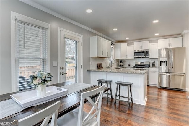 1361 Chatley Way, Woodstock, GA 30188 - kitchen with stainless steel appliances, a peninsula, crown molding, white cabinetry, and dark wood-style flooring