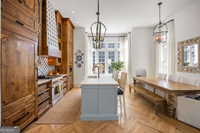 11277 Serenbe Ln, Chattahoochee Hills, GA 30268 - kitchen with a chandelier, high end stove, light countertops, a kitchen island with sink, and recessed lighting