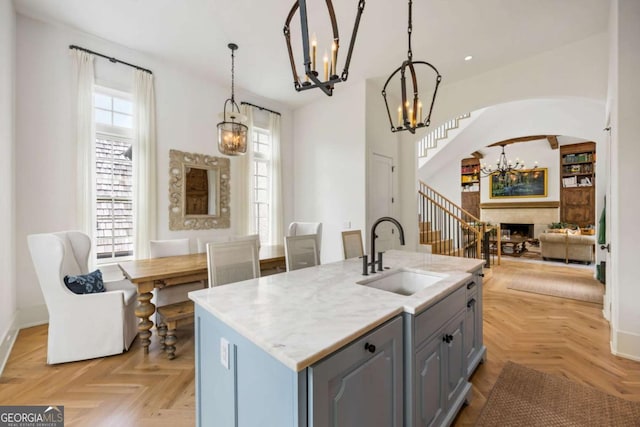 11277 Serenbe Ln, Chattahoochee Hills, GA 30268 - kitchen featuring a chandelier, gray cabinetry, arched walkways, a fireplace, and hanging light fixtures