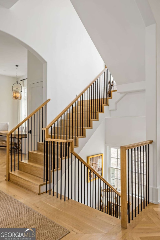 11277 Serenbe Ln, Chattahoochee Hills, GA 30268 - stairway with a chandelier, arched walkways, a towering ceiling, and recessed lighting