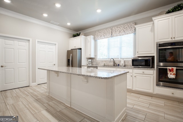 3209 Telhurst Way, Buford, GA 30519 - kitchen featuring appliances with stainless steel finishes, crown molding, a kitchen island, light stone countertops, and tasteful backsplash