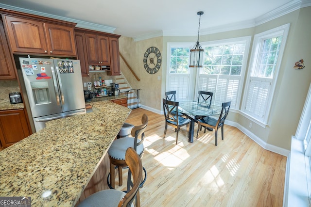 97 Windermere Cir, Newnan, GA 30265 - kitchen featuring stainless steel refrigerator with ice dispenser, healthy amount of natural light, a breakfast bar area, light stone counters, and ornamental molding