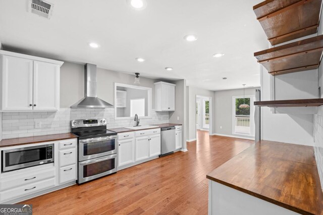 1501 Cayla Way, Statesboro, GA 30458 - kitchen with appliances with stainless steel finishes, wall chimney range hood, backsplash, white cabinets, and recessed lighting