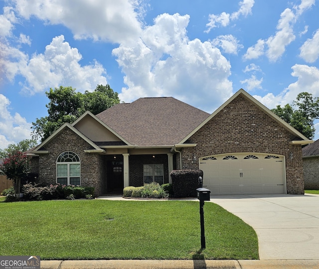 303 Norfolk Cir, Warner Robins, GA 31088 - view of front of home featuring an attached garage, brick siding, a front lawn, concrete driveway, and roof with shingles