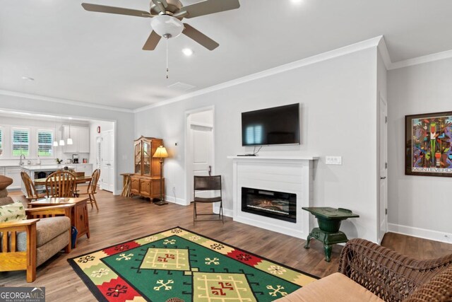 1290 Starboard Way, Greensboro, GA 30642 - living room with a ceiling fan, crown molding, wood finished floors, and a glass covered fireplace