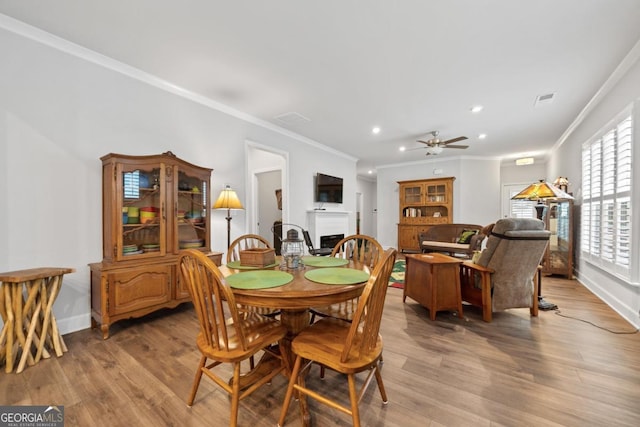 1290 Starboard Way, Greensboro, GA 30642 - dining space with a fireplace, ornamental molding, a ceiling fan, light wood-style floors, and recessed lighting