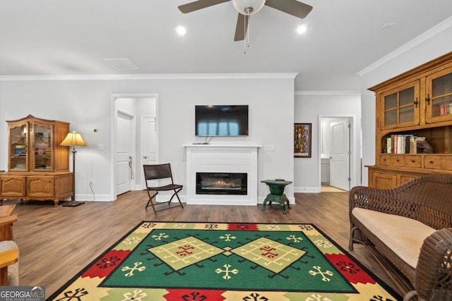 1290 Starboard Way, Greensboro, GA 30642 - living area featuring ornamental molding, wood finished floors, ceiling fan, and a glass covered fireplace