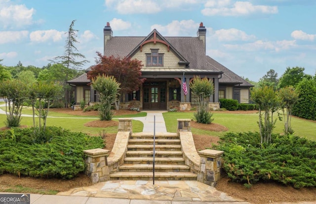 4266 Azalea Ridge Way, Hoschton, GA 30548 - view of front of house featuring french doors, covered porch, a front lawn, a chimney, and stone siding