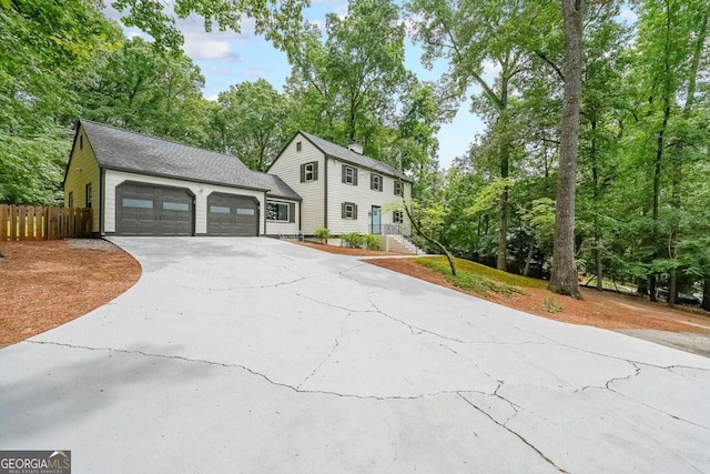 9805 Buice Rd, Alpharetta, GA 30022 - view of front of home with concrete driveway, a garage, view of scattered trees, and a chimney