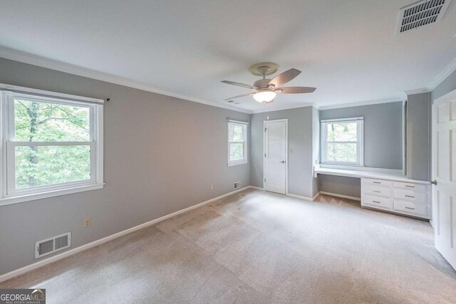 9805 Buice Rd, Alpharetta, GA 30022 - unfurnished bedroom featuring multiple windows, ornamental molding, light colored carpet, built in study area, and ceiling fan