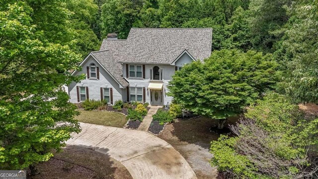 9805 Buice Rd, Alpharetta, GA 30022 - view of front of property with stucco siding, a chimney, roof with shingles, and a forest view