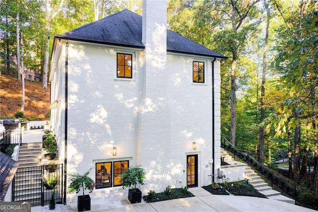 6090 River Chase Cir, Atlanta, GA 30328 - view of home's exterior featuring stairway, a chimney, and roof with shingles