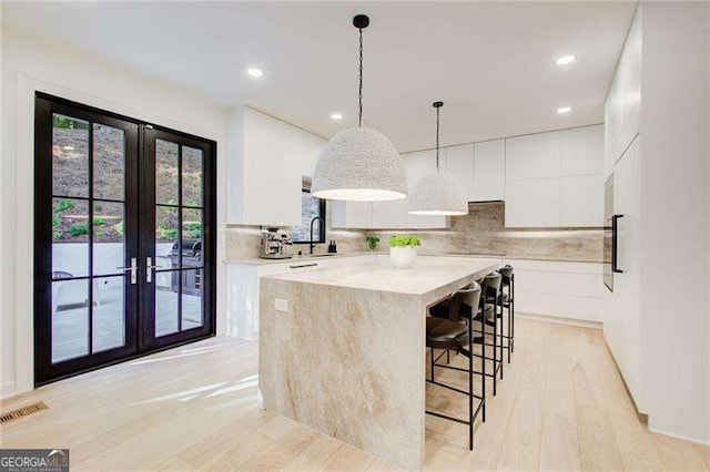 6090 River Chase Cir, Atlanta, GA 30328 - kitchen with french doors, light countertops, a kitchen island, white cabinets, and light wood-style flooring