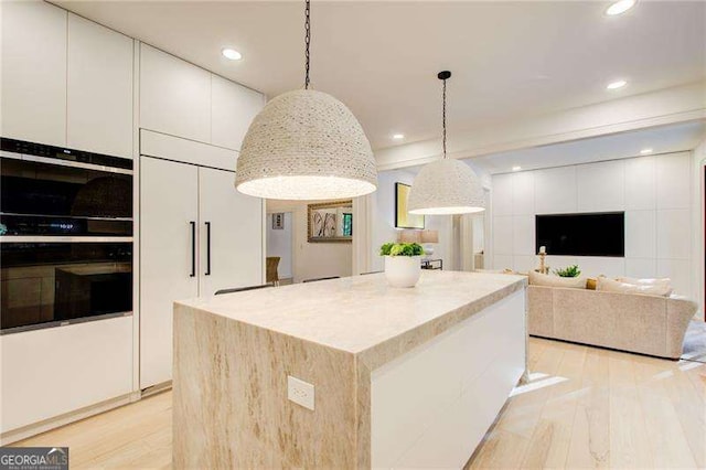 6090 River Chase Cir, Atlanta, GA 30328 - kitchen featuring light wood-style floors, white cabinets, hanging light fixtures, a center island, and recessed lighting
