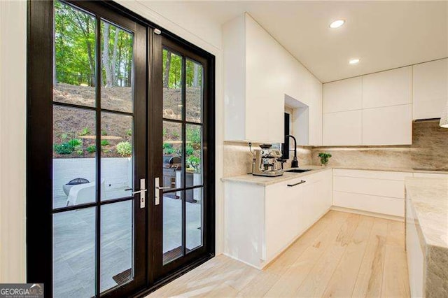6090 River Chase Cir, Atlanta, GA 30328 - kitchen featuring light wood-style flooring, light countertops, white cabinets, decorative backsplash, and french doors