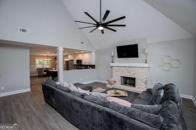 328 Brookstone Dr, Carrollton, GA 30116 - living area with high vaulted ceiling, dark wood-style flooring, ceiling fan, a brick fireplace, and a chandelier
