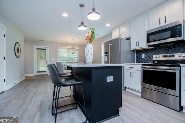328 Brookstone Dr, Carrollton, GA 30116 - kitchen featuring stainless steel appliances, white cabinets, a center island, light wood-style floors, and decorative backsplash